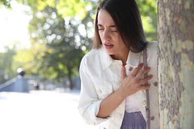 Young woman having heart attack in park