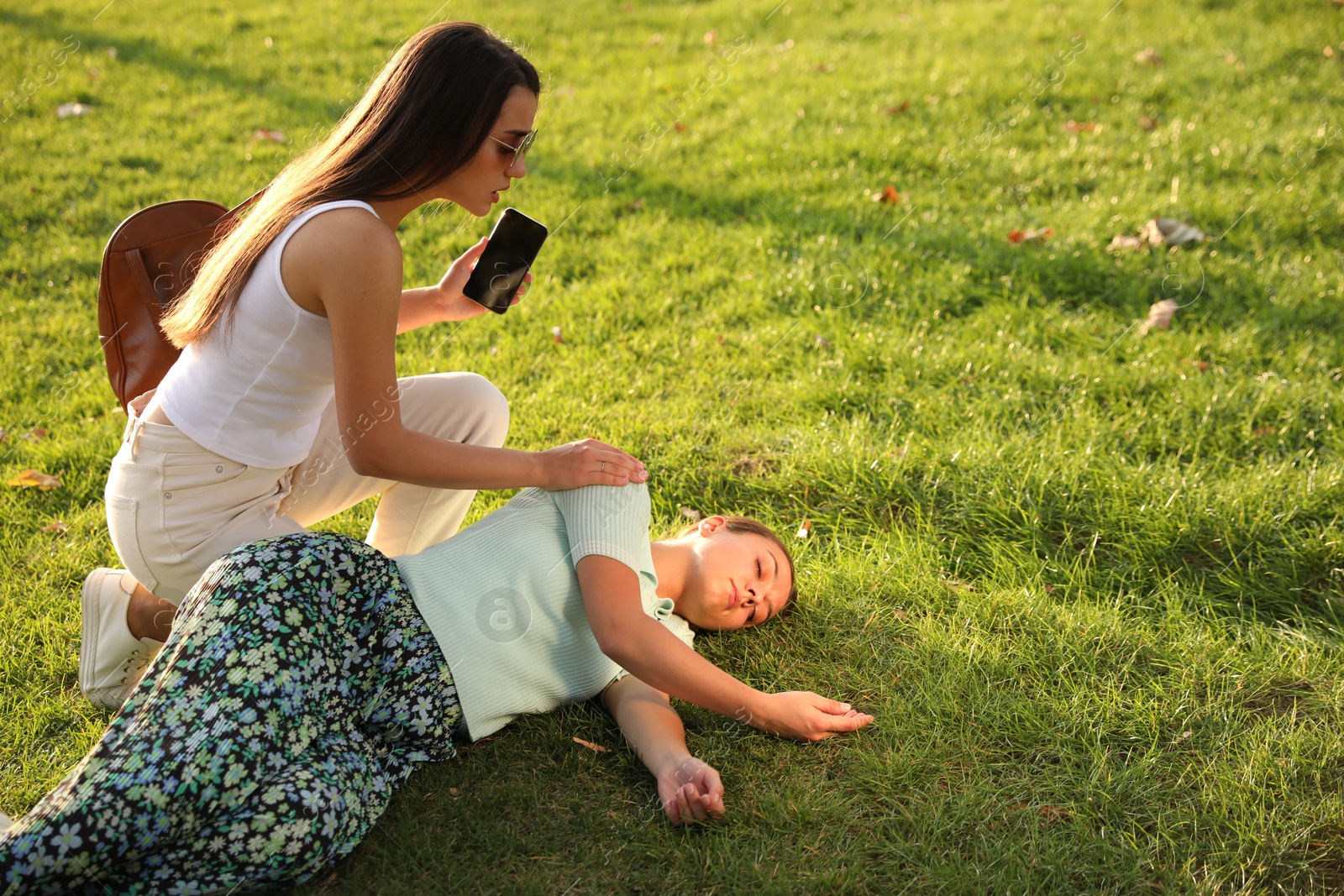 Photo of Woman calling ambulance to help unconscious person with heart attack in park