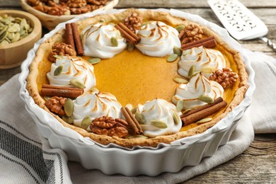 Photo of Tasty homemade pumpkin pie in baking dish on wooden table, closeup