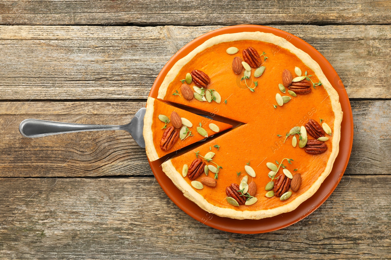 Photo of Tasty homemade pumpkin pie and server on wooden table, top view