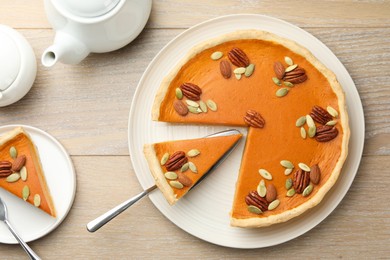 Photo of Tasty homemade pumpkin pie served on wooden table, top view