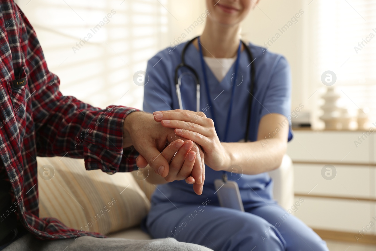 Photo of Caregiver supporting senior woman indoors, closeup. Home health care service