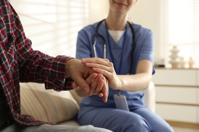 Photo of Caregiver supporting senior woman indoors, closeup. Home health care service