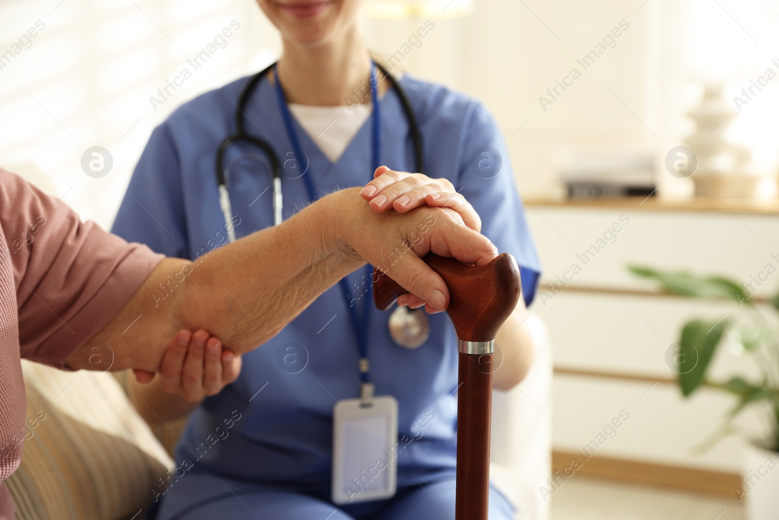 Photo of Caregiver supporting senior woman indoors, closeup. Home health care service