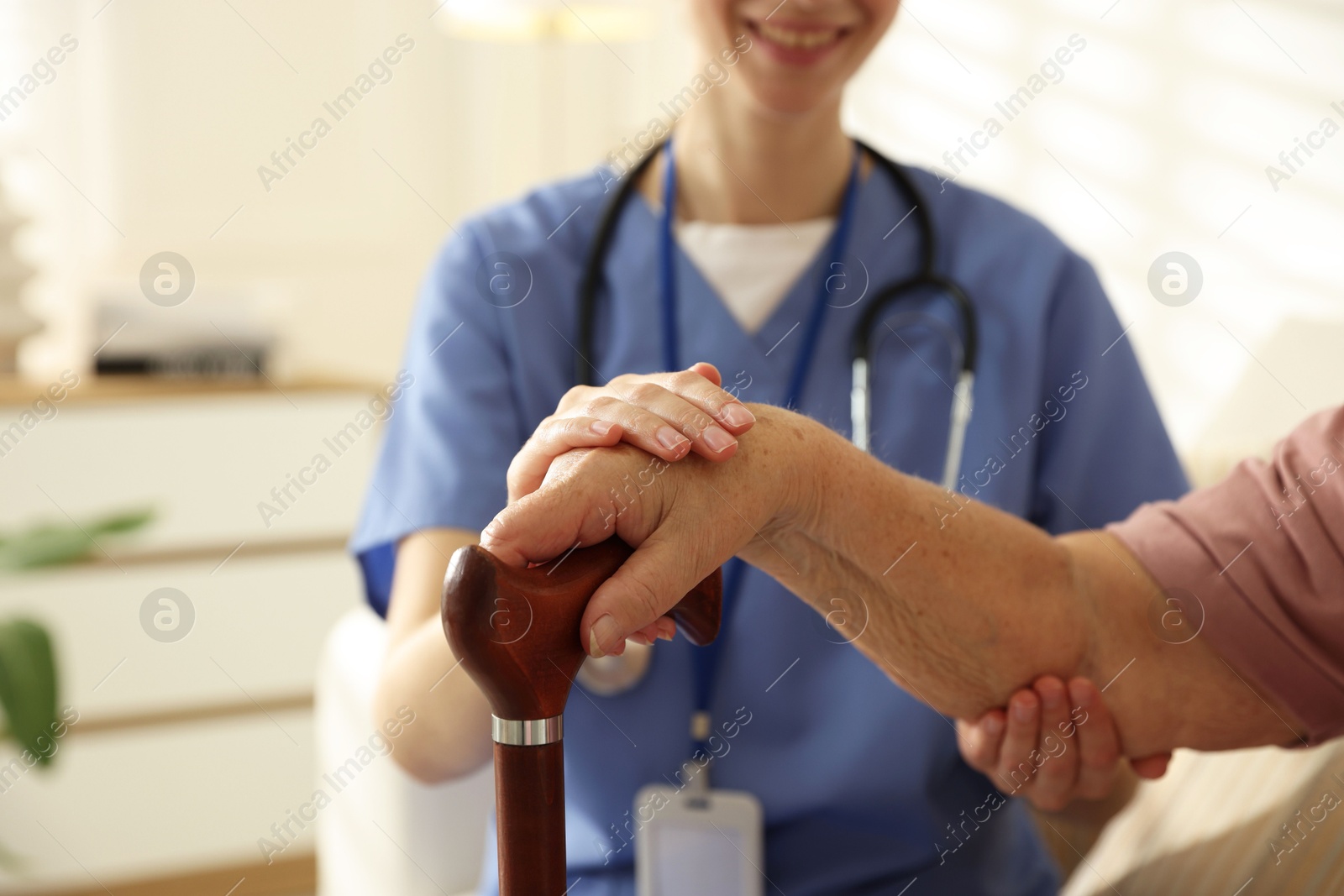 Photo of Caregiver supporting senior woman indoors, closeup. Home health care service