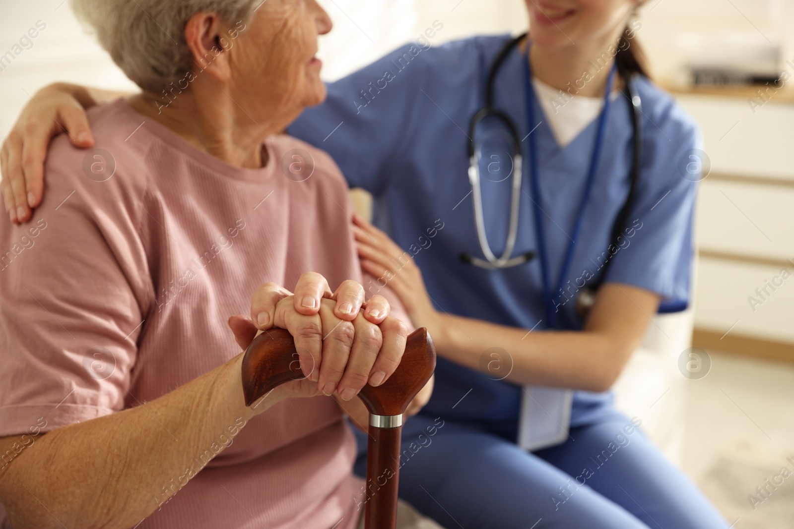 Photo of Caregiver supporting senior woman indoors, closeup. Home health care service