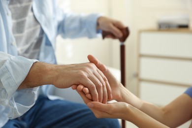 Photo of Caregiver supporting senior man indoors, closeup. Home health care service