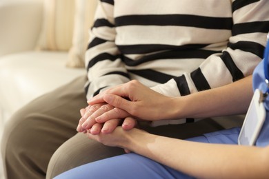 Photo of Caregiver supporting senior woman indoors, closeup. Home health care service