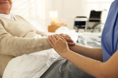 Photo of Caregiver supporting senior woman indoors, closeup. Home health care service