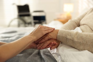 Photo of Caregiver supporting senior woman indoors, closeup. Home health care service