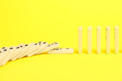 Photo of Domino effect. Tiles falling on yellow background