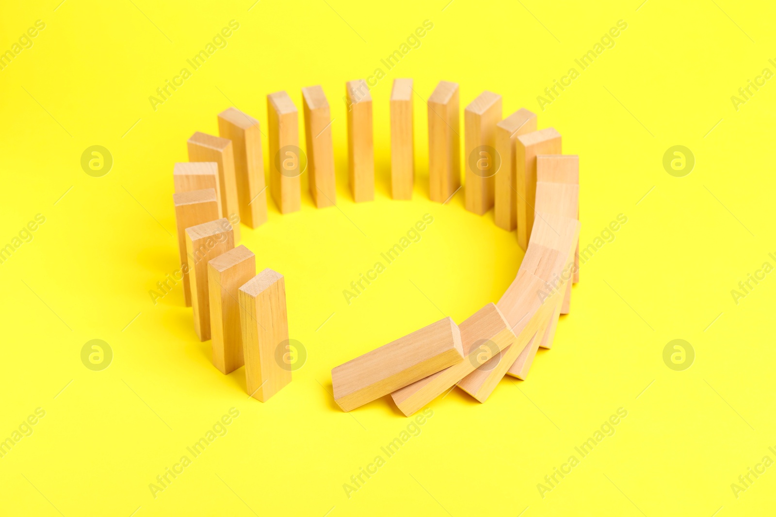 Photo of Domino effect. Wooden blocks falling on yellow background