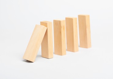 Photo of Domino effect. Wooden blocks falling on light background