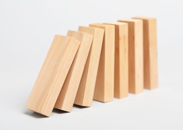 Photo of Domino effect. Wooden blocks falling on light background