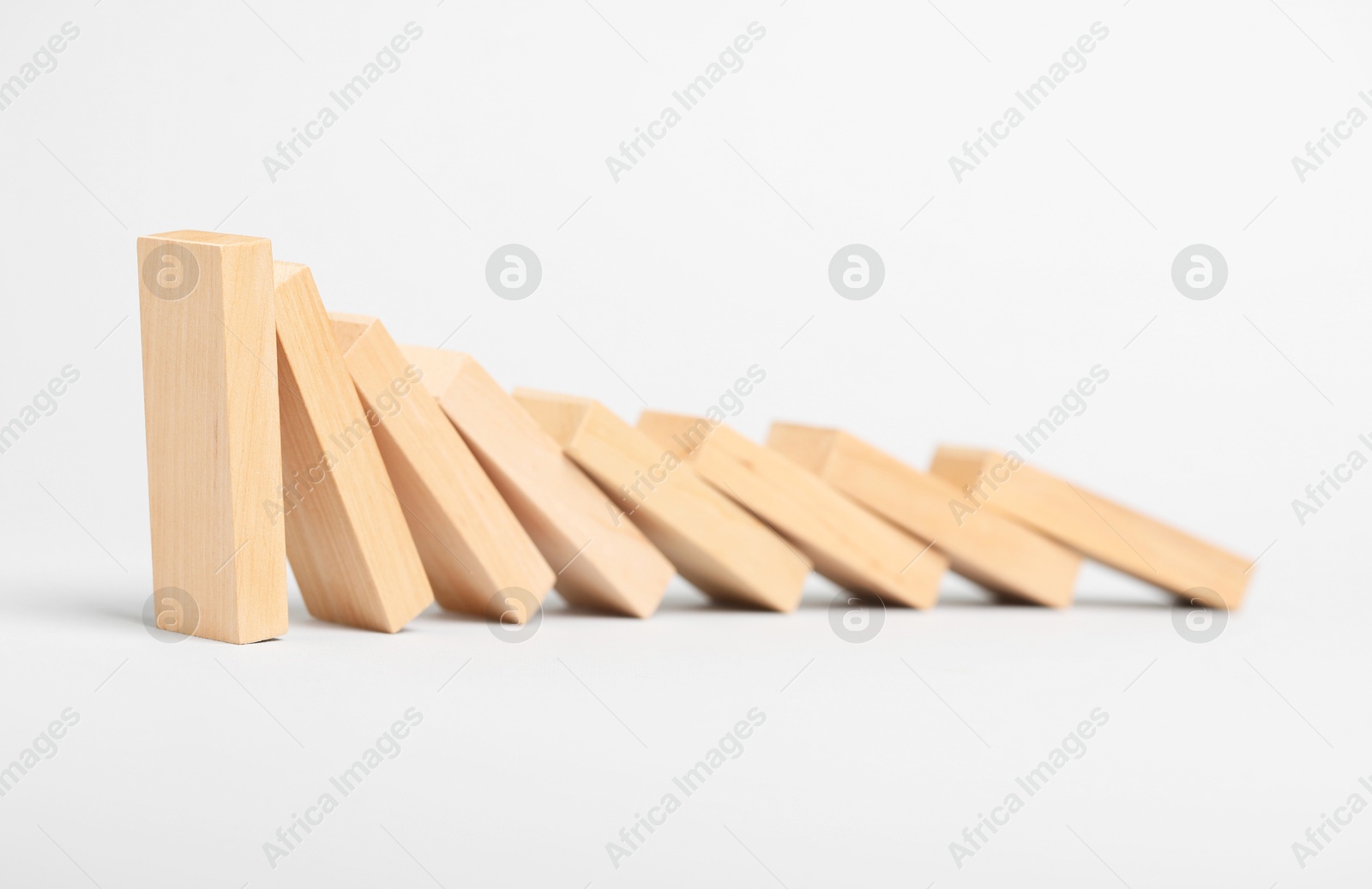 Photo of Domino effect. Wooden blocks falling on light background