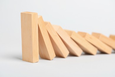 Photo of Domino effect. Wooden blocks falling on light background, closeup