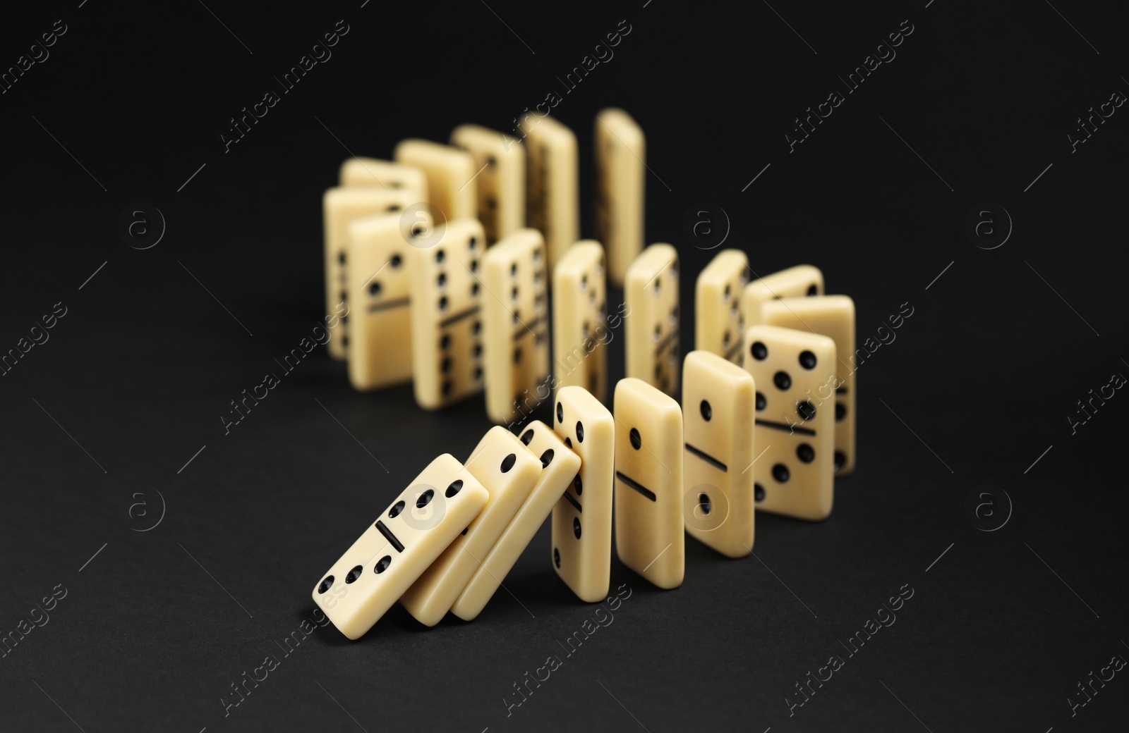 Photo of Domino effect. Tiles falling on black background