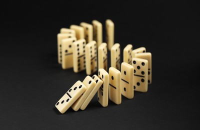 Photo of Domino effect. Tiles falling on black background