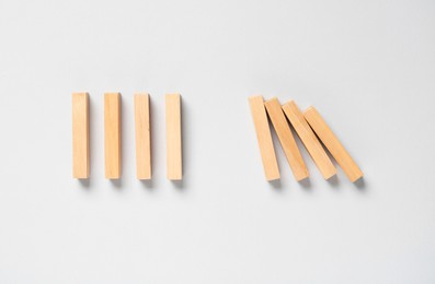 Photo of Domino effect. Wooden blocks on light background, flat lay