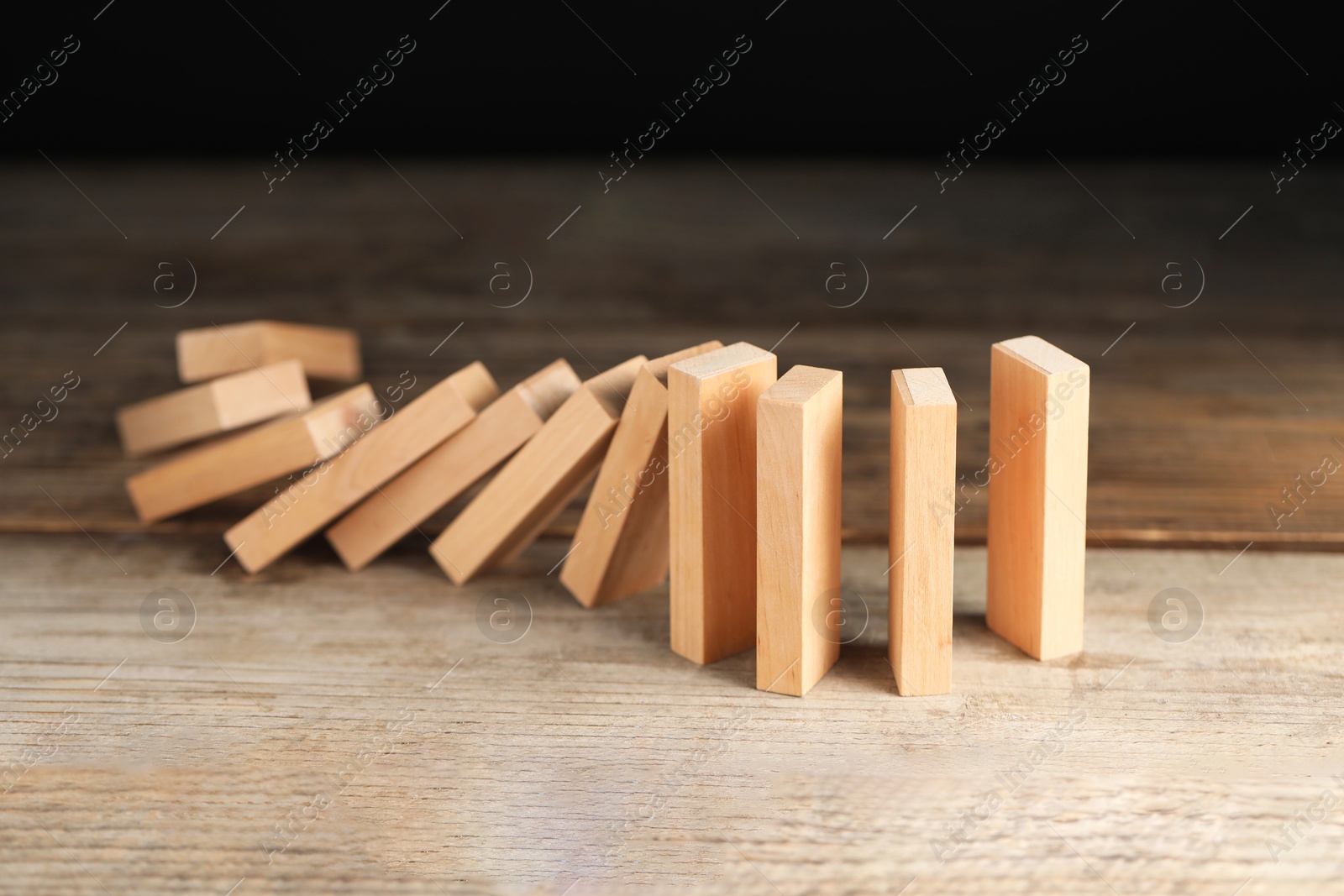 Photo of Domino effect. Wooden blocks falling on table