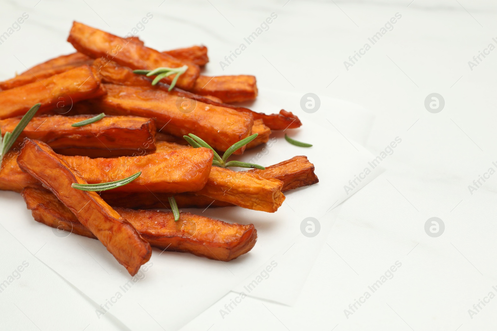 Photo of Delicious sweet potato fries with rosemary on white table, closeup. Space for text