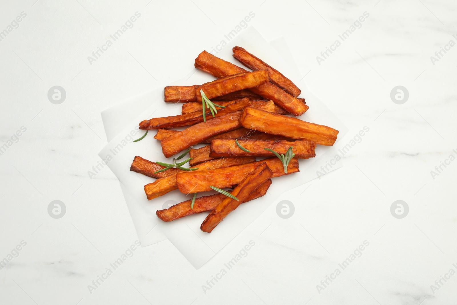 Photo of Delicious sweet potato fries with rosemary on white marble table, top view