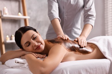 Photo of Woman undergoing chocolate body wrap treatment in spa salon