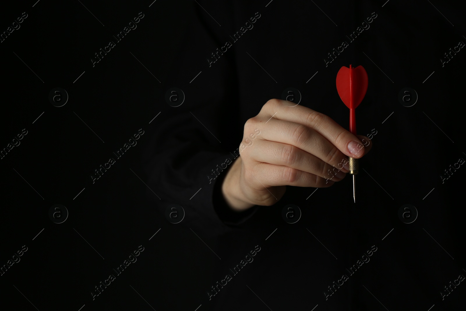 Photo of Woman holding dart on black background, closeup