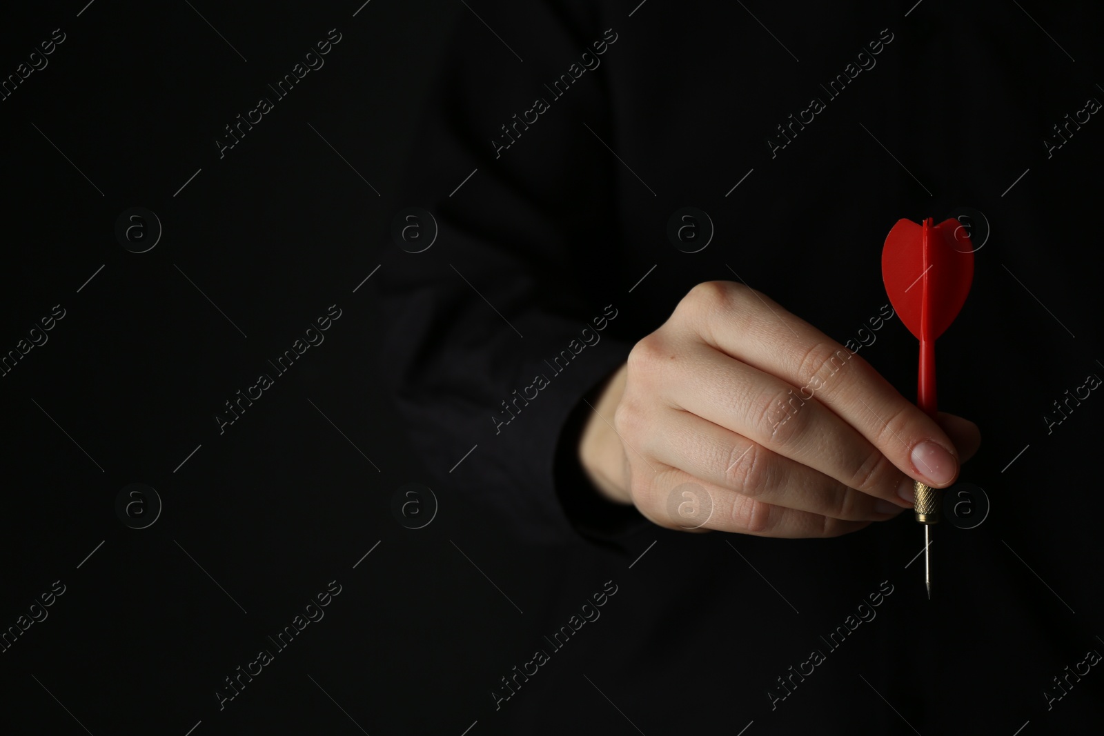 Photo of Woman holding dart on black background, closeup