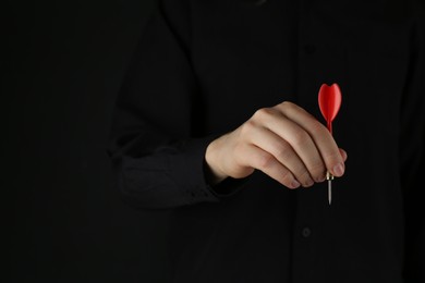 Photo of Woman holding dart on black background, closeup