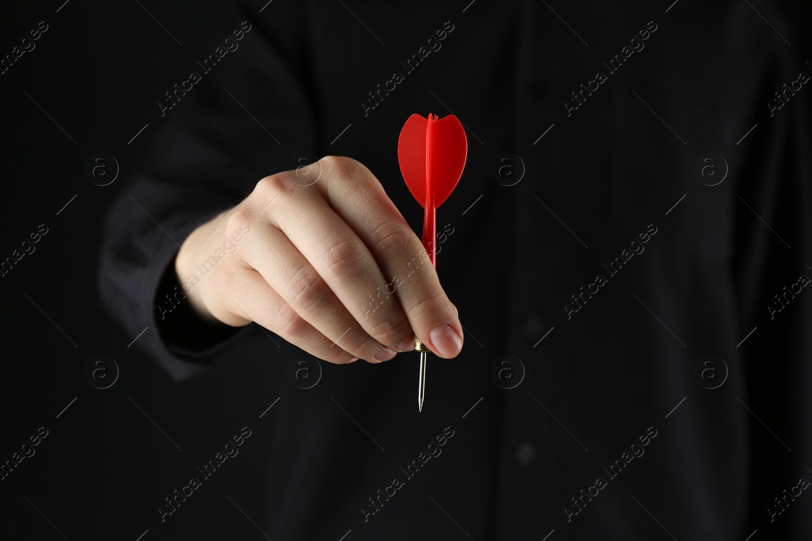 Photo of Woman holding dart on black background, closeup