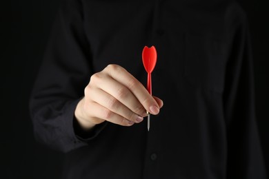 Photo of Woman holding dart on black background, closeup