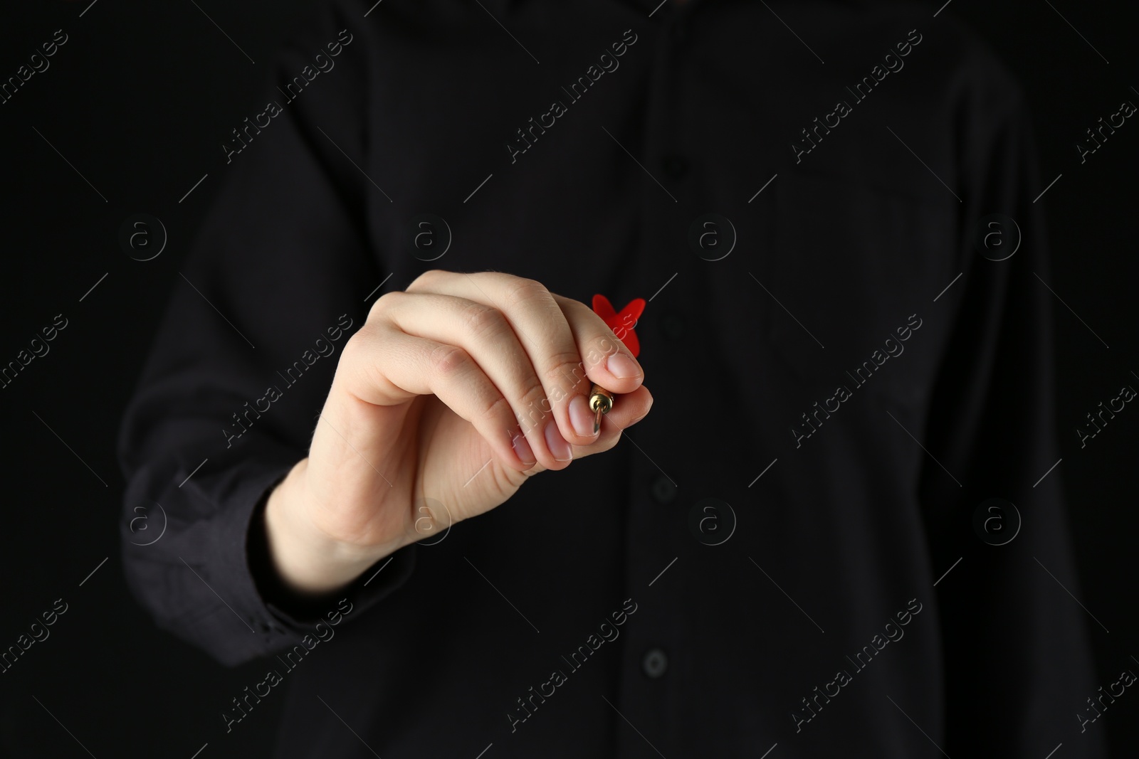 Photo of Woman holding dart on black background, closeup