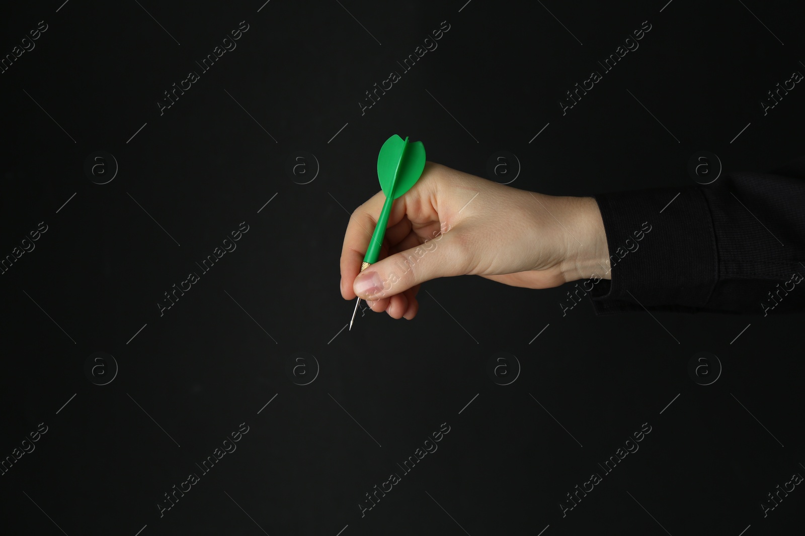 Photo of Woman holding dart on black background, closeup. Space for text