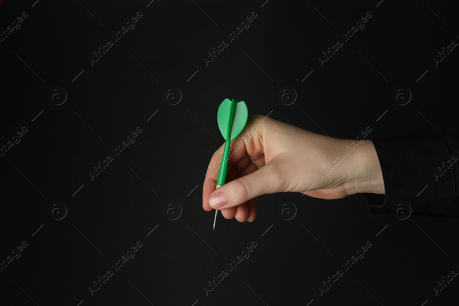 Photo of Woman holding dart on black background, closeup. Space for text