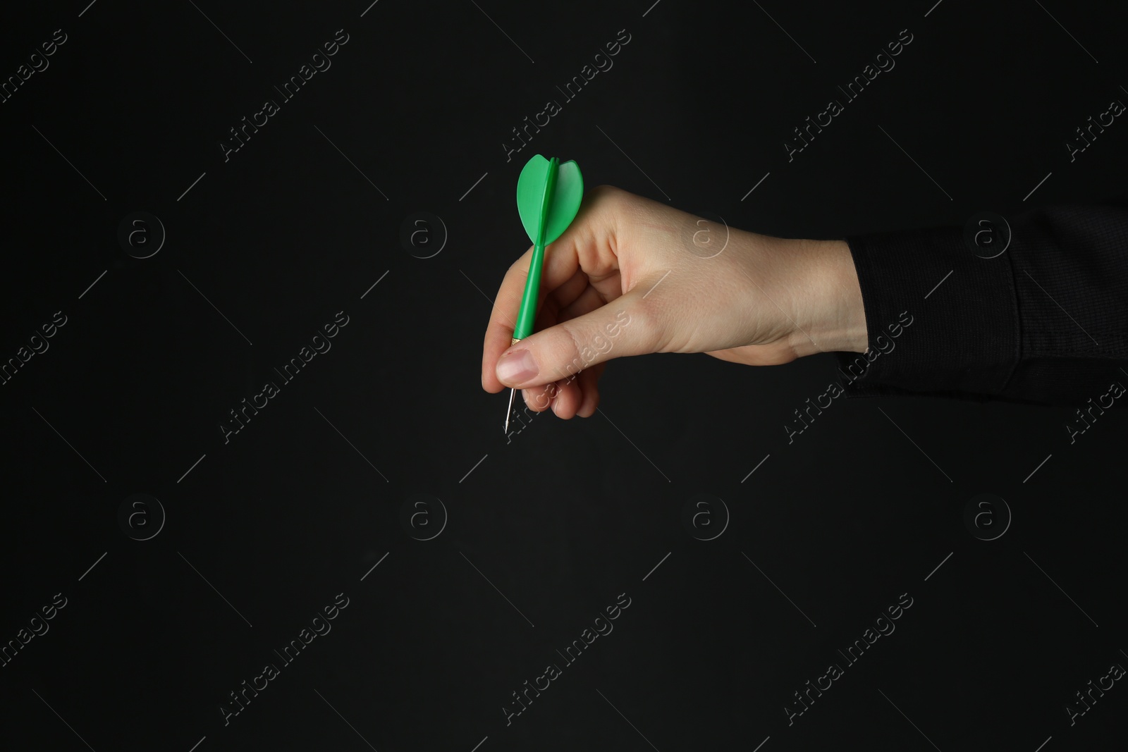 Photo of Woman holding dart on black background, closeup. Space for text