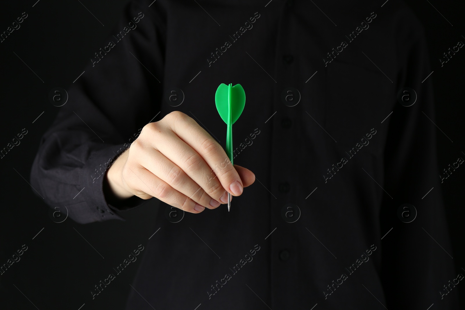 Photo of Woman holding dart on black background, closeup