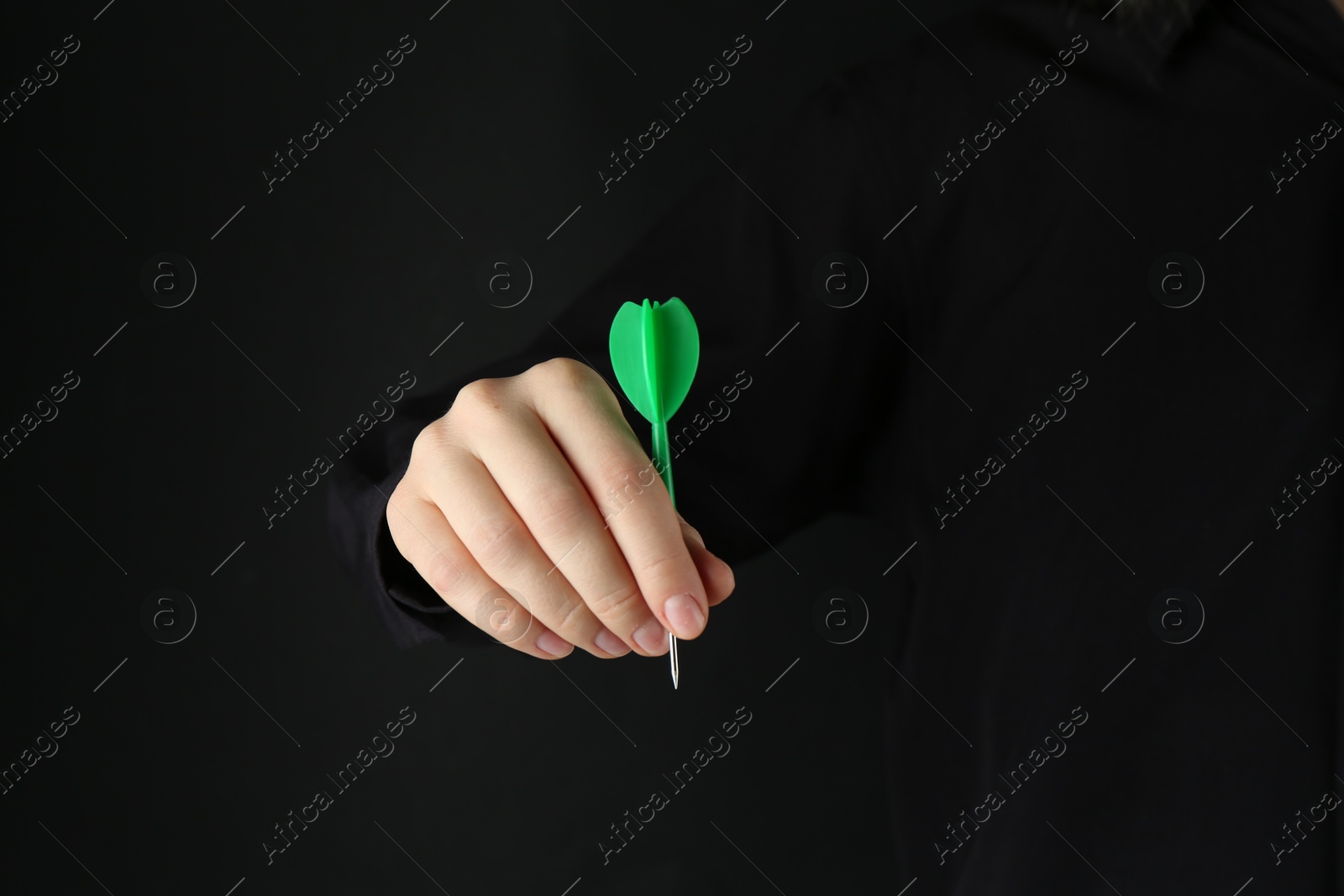 Photo of Woman holding dart on black background, closeup