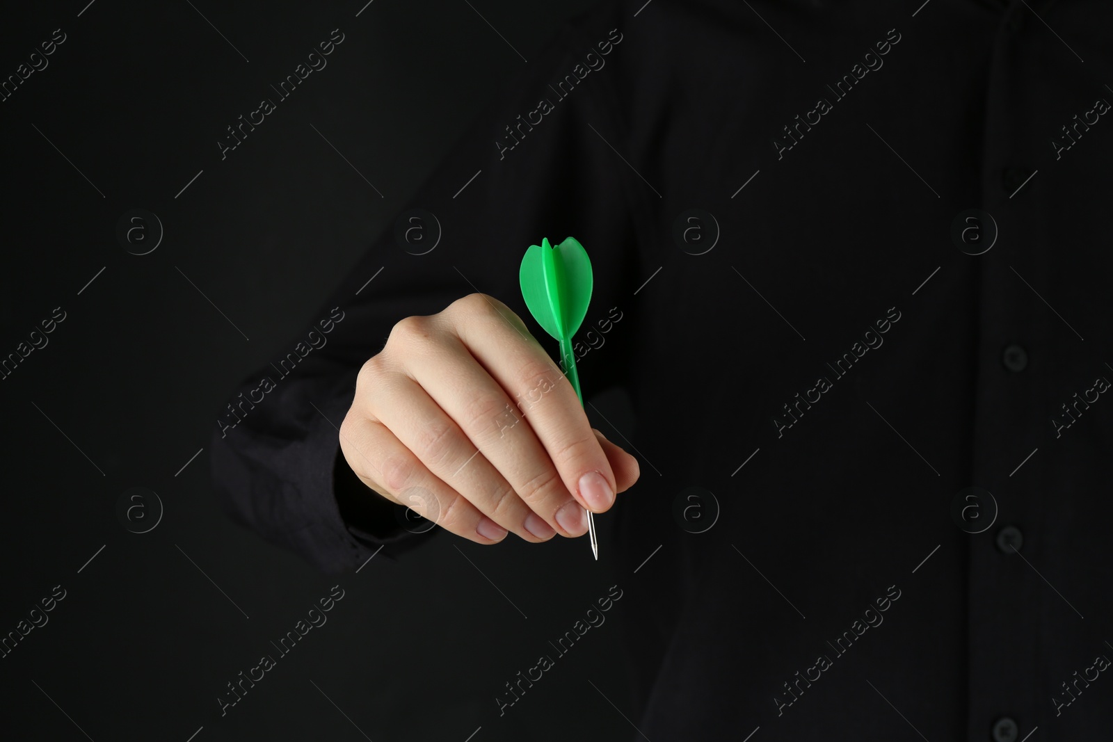 Photo of Woman holding dart on black background, closeup