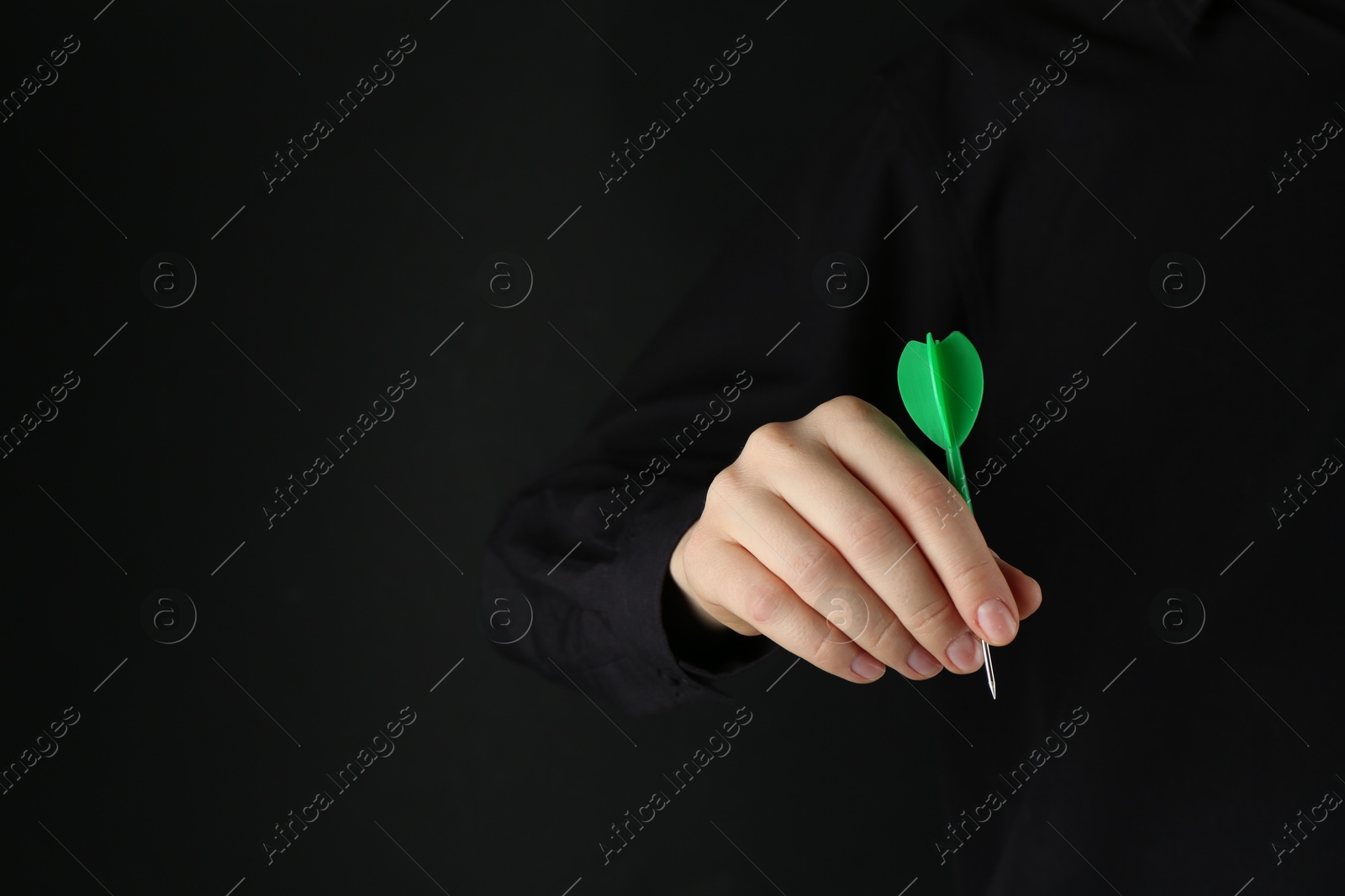 Photo of Woman holding dart on black background, closeup