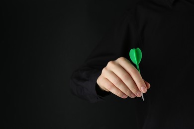 Photo of Woman holding dart on black background, closeup