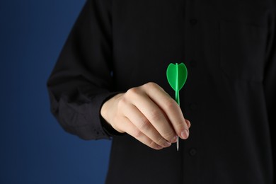 Photo of Woman holding dart on blue background, closeup