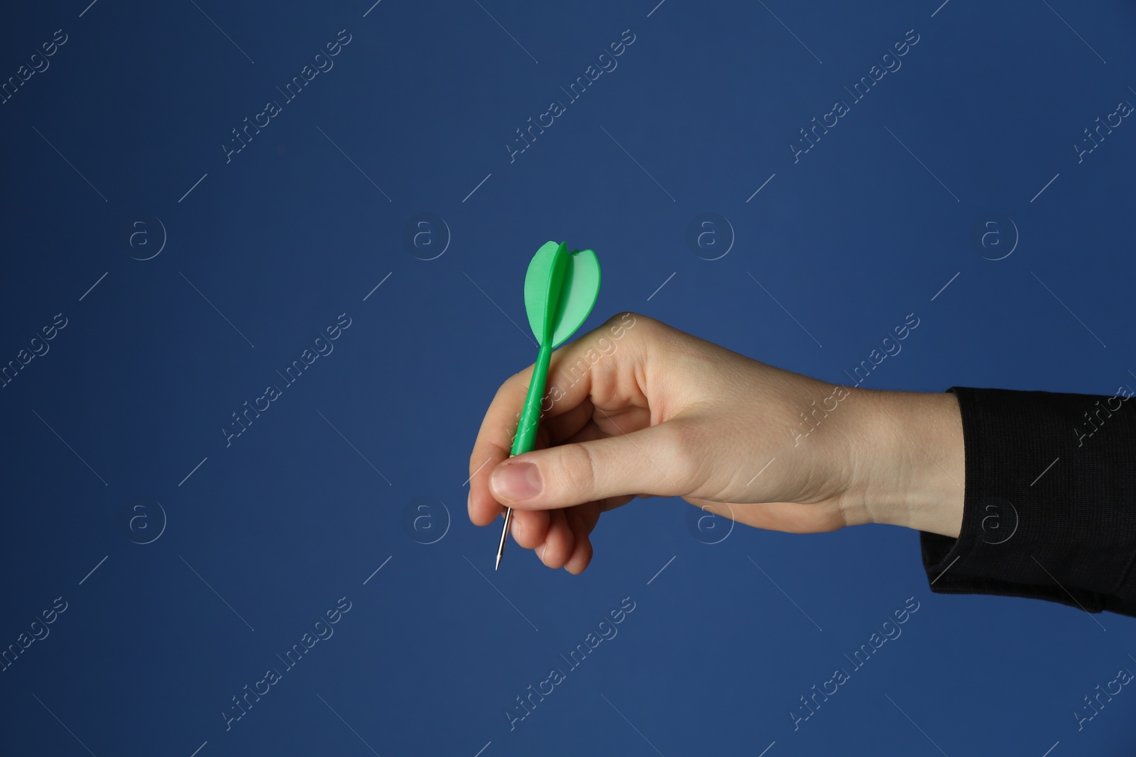 Photo of Woman holding dart on blue background, closeup. Space for text