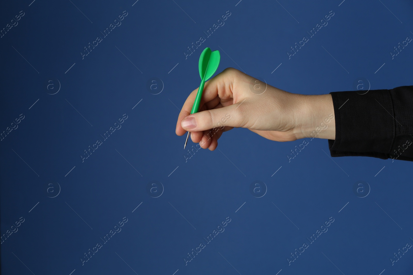 Photo of Woman holding dart on blue background, closeup. Space for text