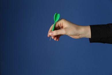 Photo of Woman holding dart on blue background, closeup. Space for text