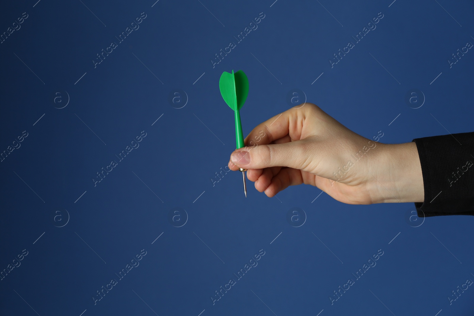 Photo of Woman holding dart on blue background, closeup. Space for text