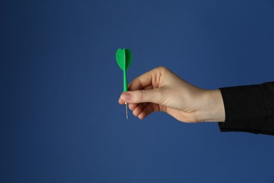 Photo of Woman holding dart on blue background, closeup. Space for text