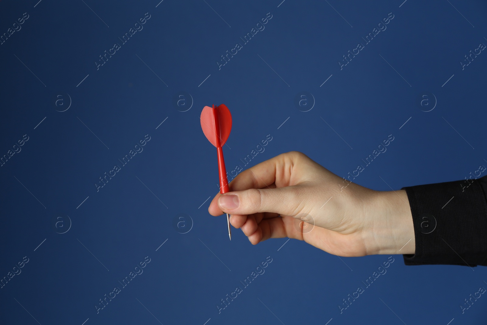 Photo of Woman holding dart on blue background, closeup. Space for text