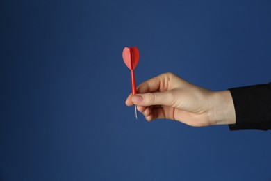 Photo of Woman holding dart on blue background, closeup. Space for text