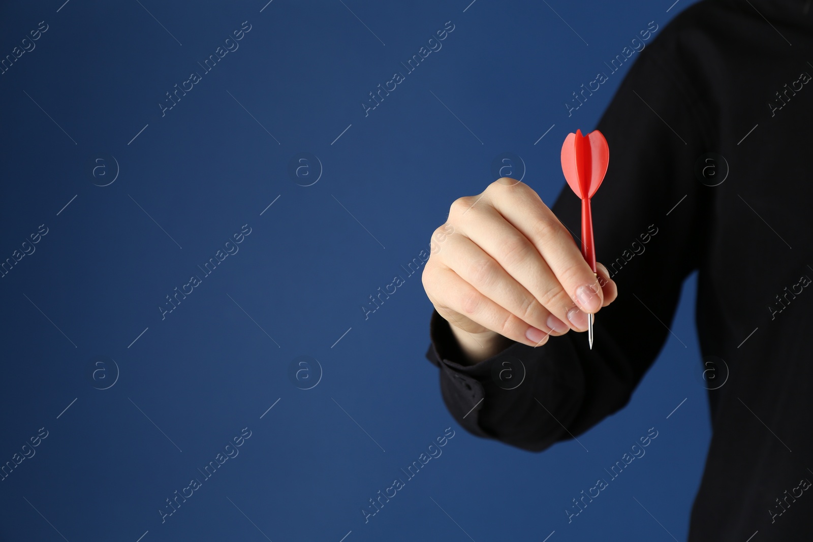 Photo of Woman holding dart on blue background, closeup. Space for text